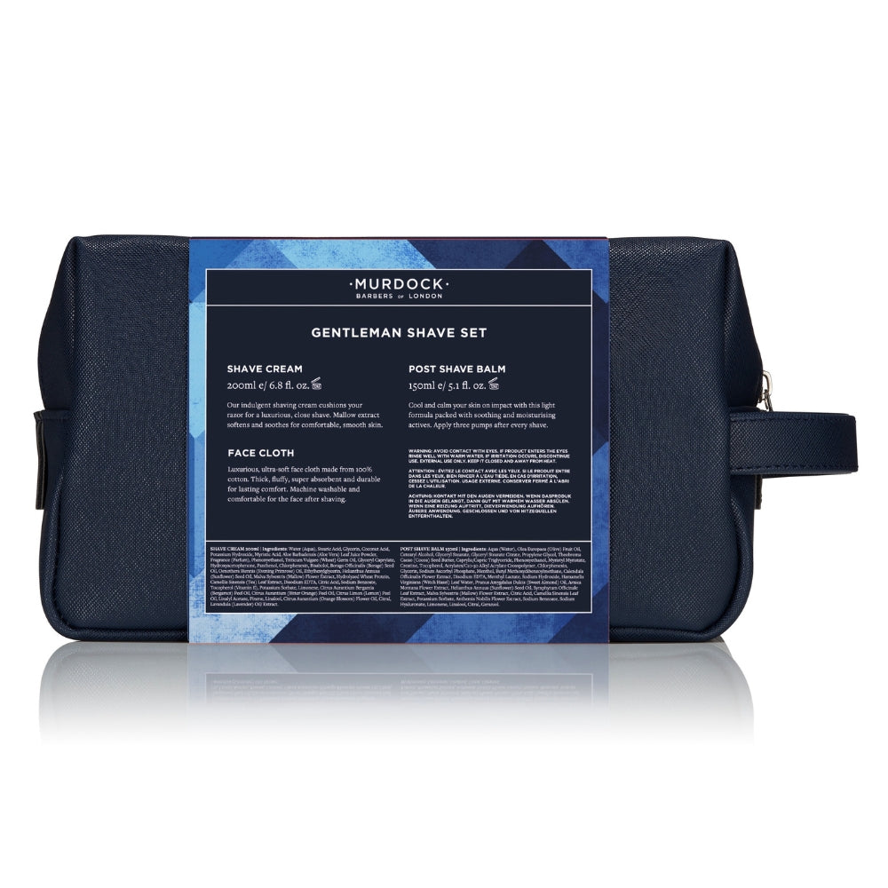 A dark navy blue Murdock London gentleman's shave set pouch with a large blue and black product information label wrapped around the front, shown on a white background with a soft reflection.